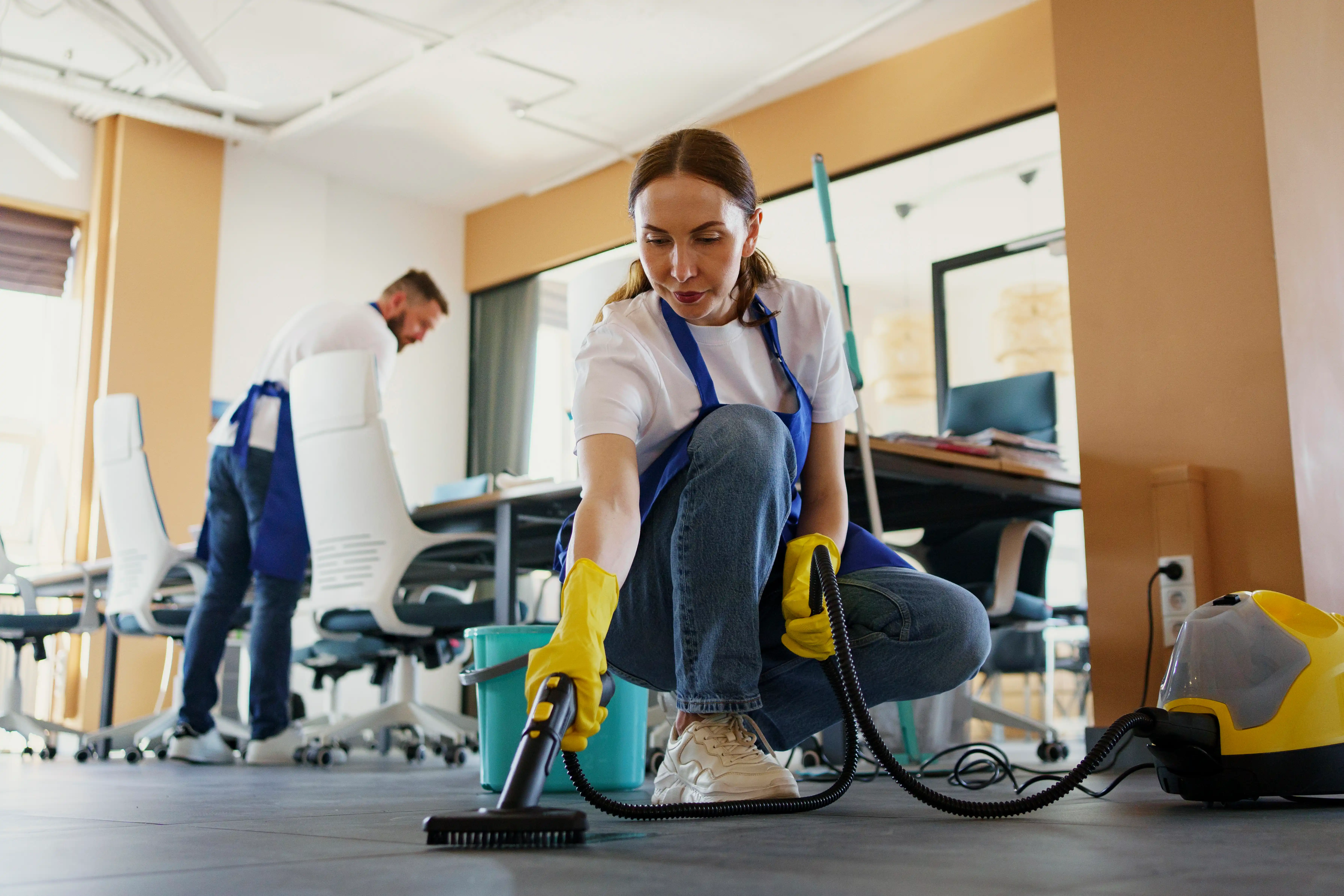 A woman using a vacuum cleaner to clean a room, focusing on maintaining a tidy and organized space.